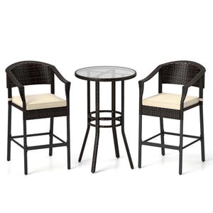 A 3-piece outdoor bar set with two wicker stools and a round glass-top table. The stools have cream cushions and black metal frames.