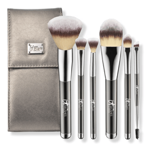 A set of six makeup brushes with metallic handles and a matching metallic case, featuring a variety of brush types including a large powder brush, foundation brush, and spoolie.