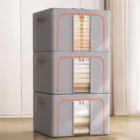 Stacked gray fabric storage drawers with red trim, showcasing towels and bed linens.