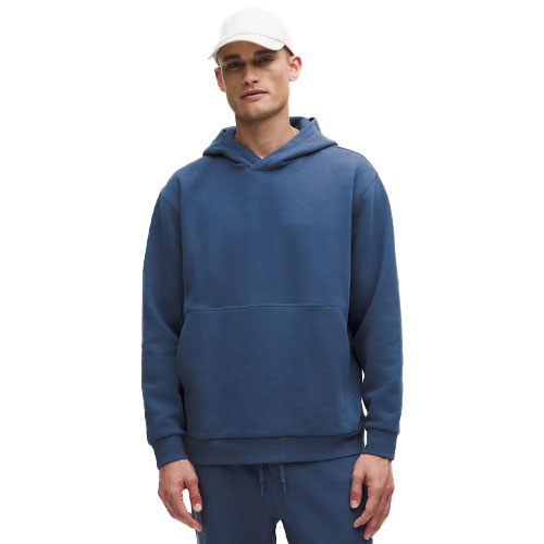 A man wearing a blue hoodie and matching sweatpants, paired with a white cap.