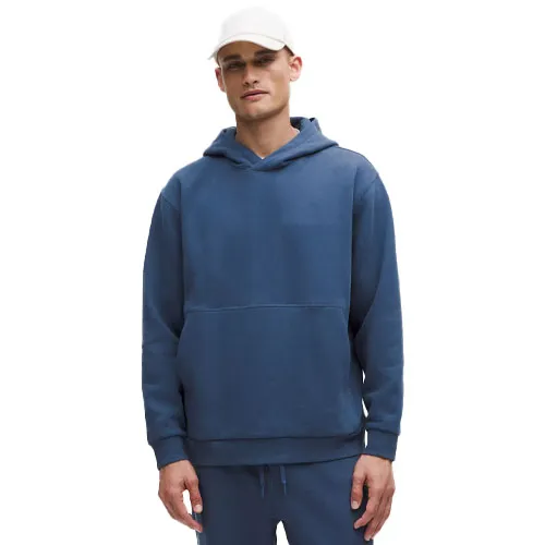 A man wearing a blue hoodie and matching sweatpants, paired with a white cap.