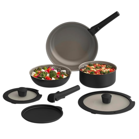 Cookware set with detachable handle, including a frying pan, two pots with glass lids, and a storage lid. Contains colorful vegetable dishes inside the pots.