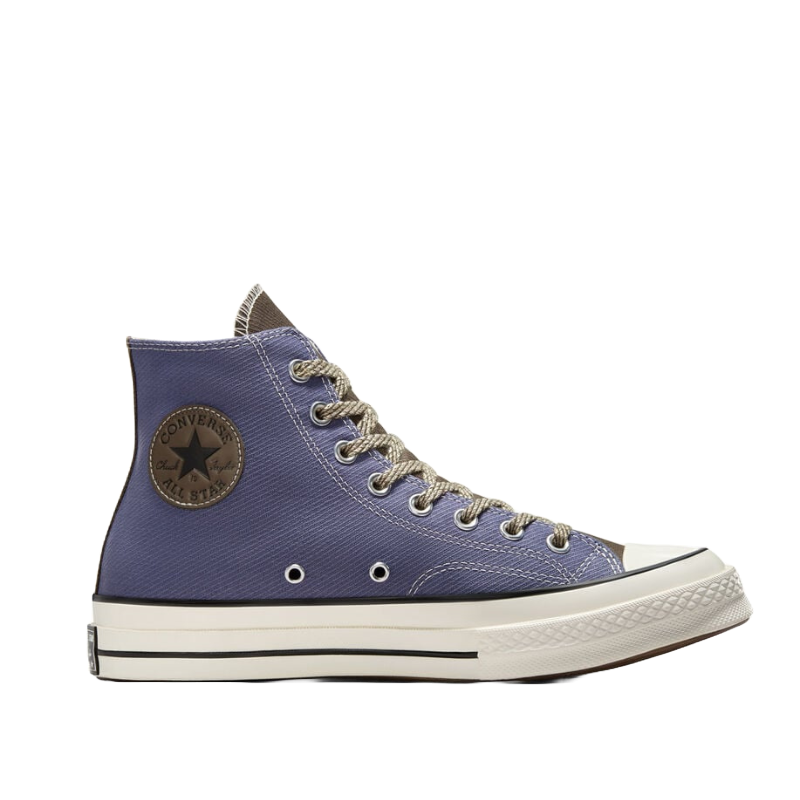 Converse Chuck 70 Dual Tone sneaker in a high-top design, featuring a blue canvas upper, brown accents, white rubber sole, and black stripe detailing. The shoe includes a circular logo patch, silver eyelets, and brown and white laces.