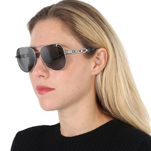 A woman is wearing aviator-style sunglasses with dark lenses and a chain-like design on the arms, paired with a black top.