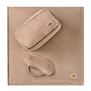 A tan travel set featuring a blanket, an eye mask, and a zippered pouch, each branded with the UGG logo.