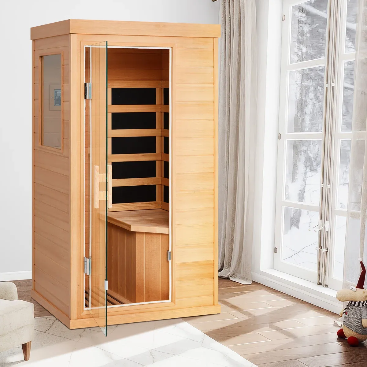 A wooden home sauna with a glass door is positioned indoors near a large window. The sauna includes a bench and control panel.