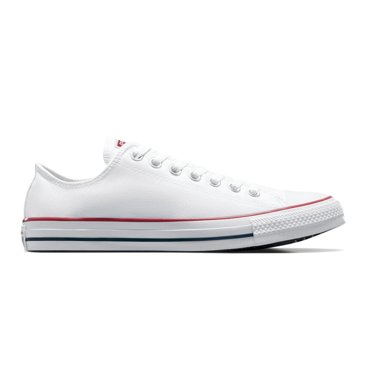 A classic low-top white canvas sneaker with white laces, featuring red and blue stripes on the rubber sole.
