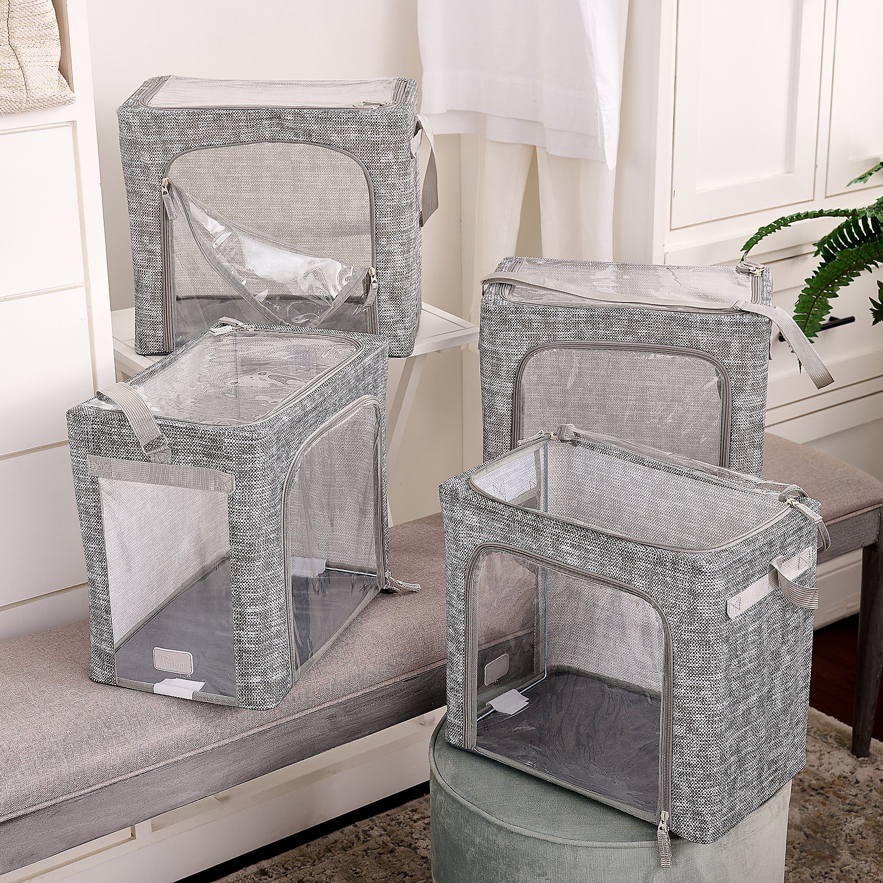 4pk Periea Collapsible Storage Boxes are gray with transparent sides and tops, featuring zippers and handles for convenience. They are structured yet foldable, ideal for organizing and storing items neatly.