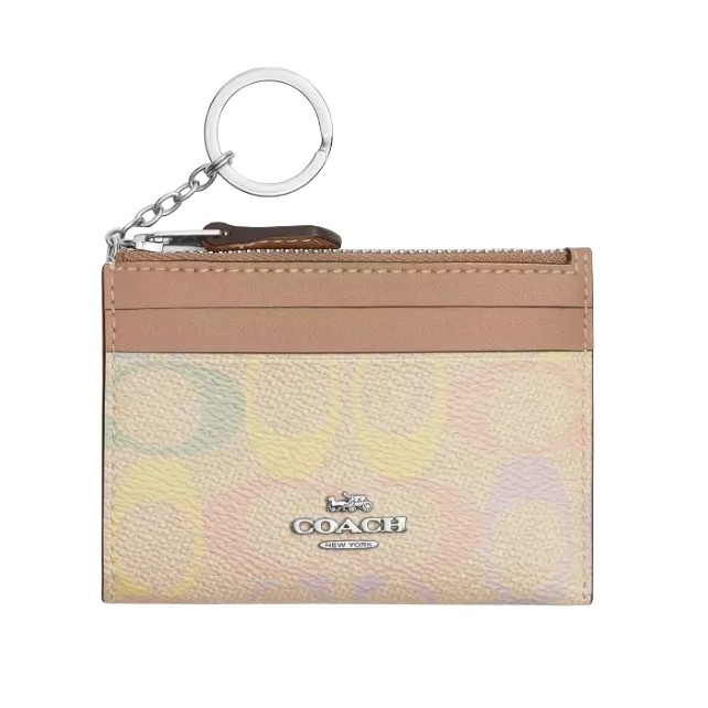 A Coach card holder with a keychain, featuring a multicolored pastel pattern and a front logo. It includes a zippered pocket and card slots.