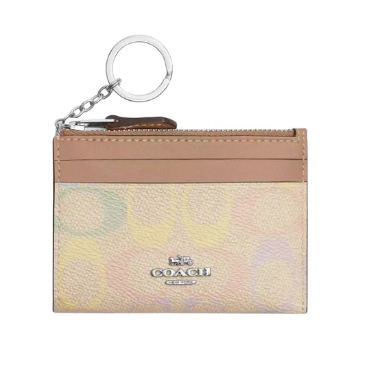 A Coach card holder with a keychain, featuring a multicolored pastel pattern and a front logo. It includes a zippered pocket and card slots.