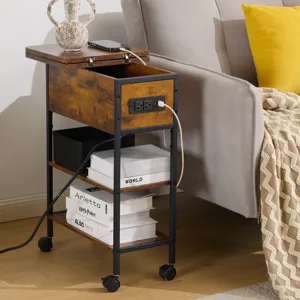 A small wooden rolling side table with a black metal frame, featuring a built-in power strip, shelves, and a top compartment. It's placed beside a sofa, decorated with a vase of tulips, and has storage boxes underneath.