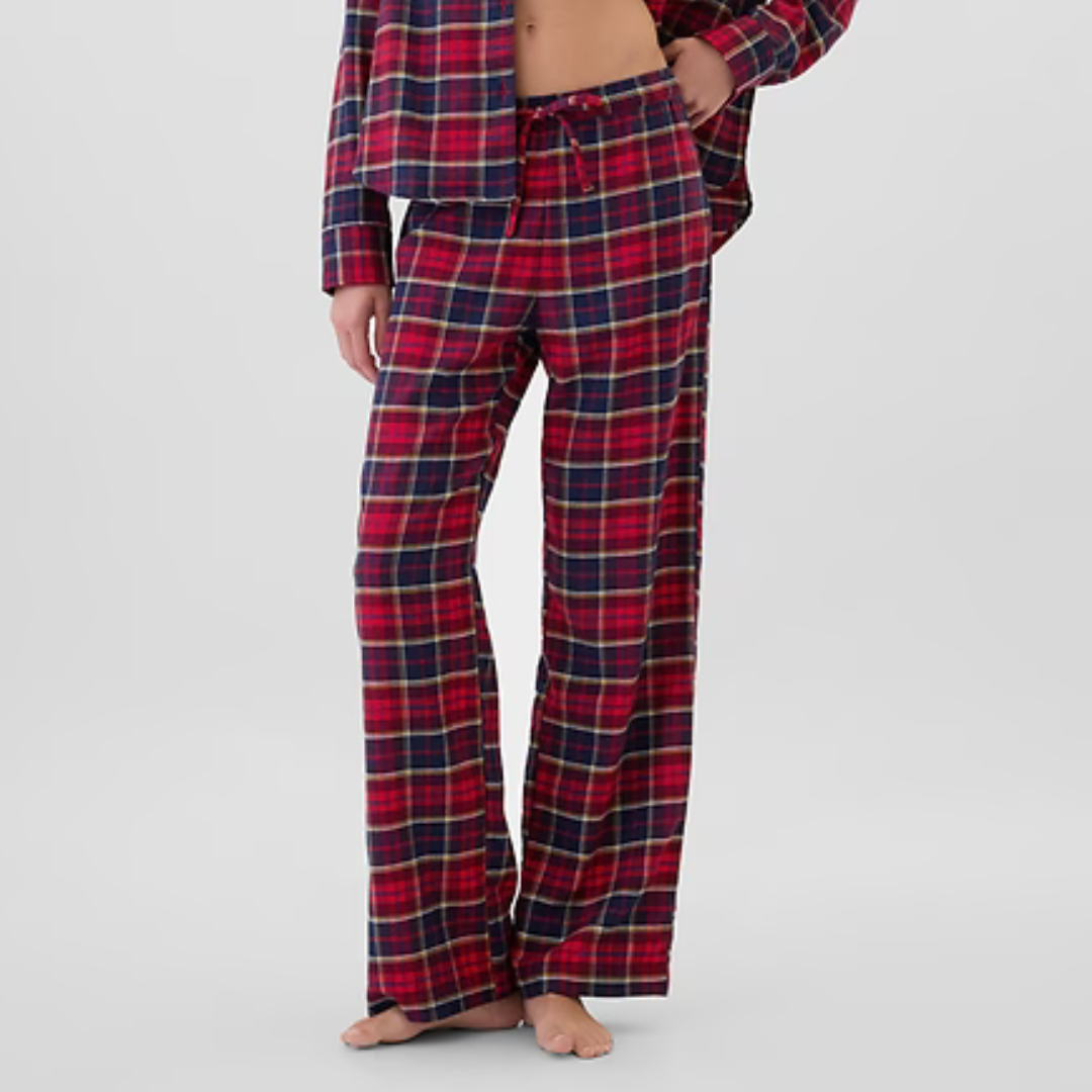 Plaid flannel pajamas consisting of loose-fitting pants and a matching button-up top; they feature a red, navy, and yellow tartan pattern.