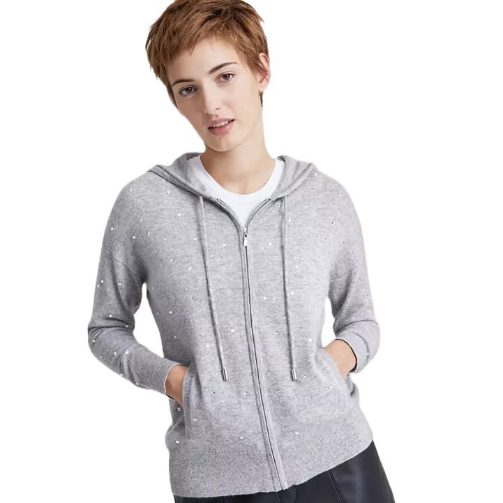 Gray zip-up hoodie with drawstrings and subtle embellishments, worn by a person over a white shirt, paired with dark pants.