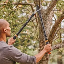 Man trimming a tree branch with Fiskars loppers featuring steel construction for durability.