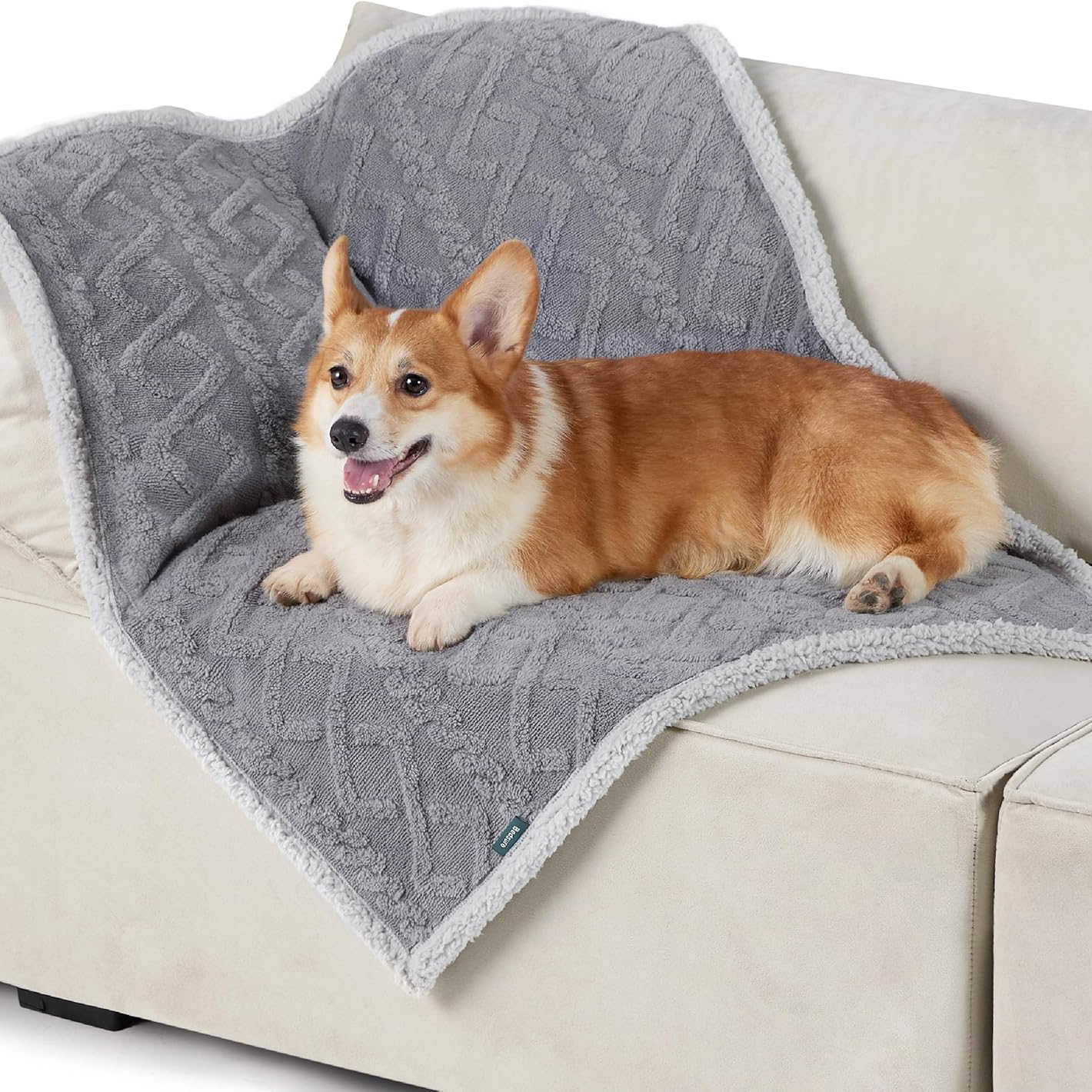 A small dog lies on a soft, plush, 30\“ x 40\“ gray blanket with a geometric pattern and a white sherpa border, draped over a light-colored couch.