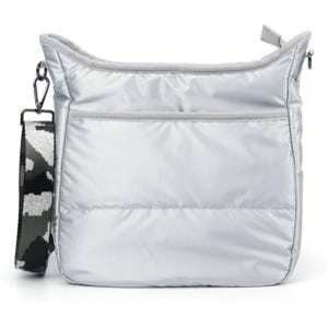 A silver quilted shoulder bag with a front pocket and a detachable black-and-white camo-patterned strap.