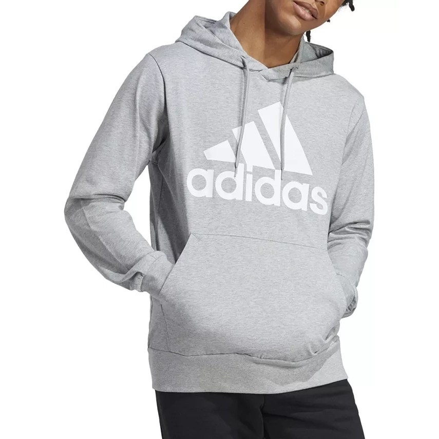 A person wearing a grey hoodie with a large Adidas logo on the front.