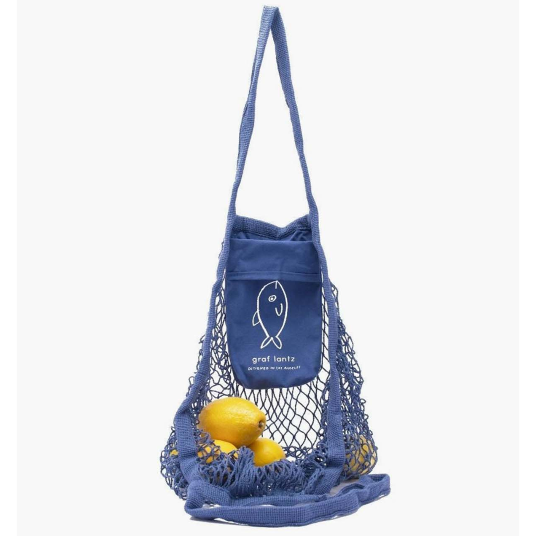 A blue netted reusable shopping bag with a solid pocket featuring a fish design, containing two lemons.