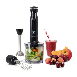 The Moss & Stone Hand Blender & Chopper is a black kitchen appliance set with interchangeable attachments, including a whisk, blender, and chopper, shown alongside a glass of smoothie and fruits.