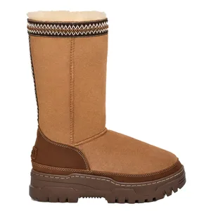 A tan, mid-calf, shearling-lined boot with a rugged, dark brown sole and decorative stitching along the top edge.