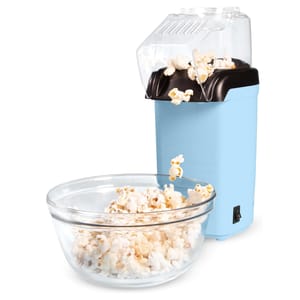 A light blue electric popcorn maker with a transparent lid is shown, dispensing popcorn into a glass bowl. The device features a simple on/off switch and an angled spout for directing popped corn.