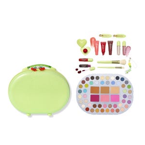 A green oval makeup case with a cherry design includes an extensive eyeshadow and blush palette, lip glosses, brushes, hair clips, and a heart-shaped accessory.