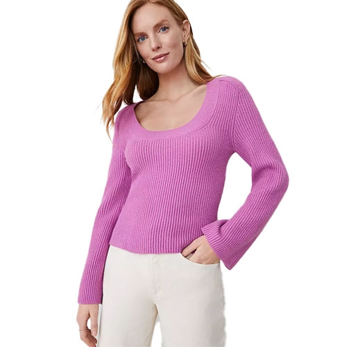 A woman is wearing a pink ribbed knit sweater with a scoop neckline and long sleeves, paired with white pants.