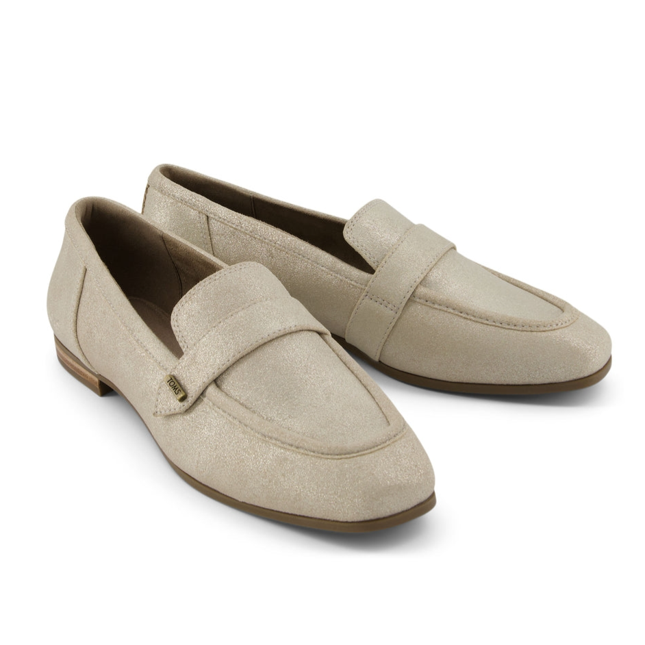 Beige loafers with a slip-on design, featuring a textured surface and a small decorative metal tag.