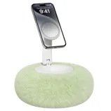 A smartphone is mounted on a fluffy, circular stand with a soft, green surface, resembling a plush cushion.