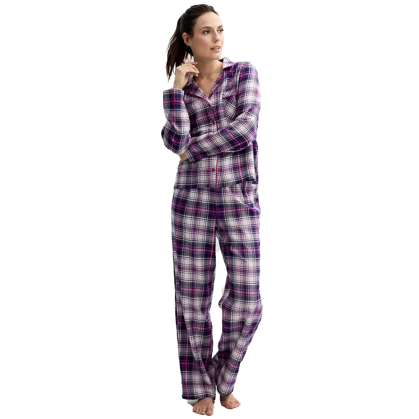A woman is wearing a plaid pajama set with a long-sleeve button-up top and matching pants in a white, purple, and pink color scheme.