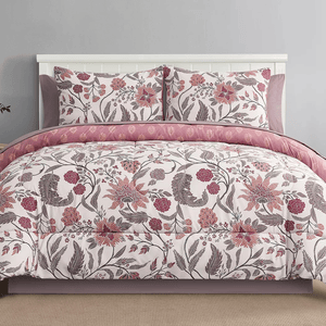 A bedding set featuring a floral pattern in pinks and purples, including a comforter and two matching pillow shams. The comforter is reversible, showing a different design on the inner side in similar color tones.