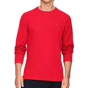 A person wearing a plain red long-sleeved crewneck shirt with a small logo on the chest.