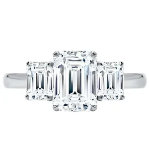 Three-stone ring with an emerald-cut center diamond flanked by two smaller emerald-cut diamonds, all set in a sleek metal band.