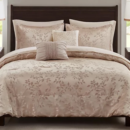A floral-patterned bedding set featuring a comforter, two large pillows, and two decorative throw pillows, all in a soft beige tone.
