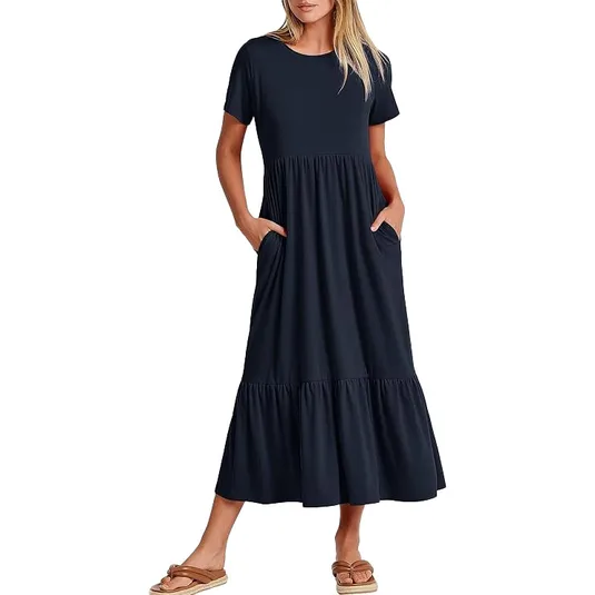 A woman is wearing a navy blue, short-sleeved midi dress with a tiered skirt and side pockets. She is also wearing flat sandals.