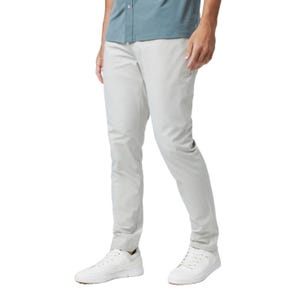 A person wearing light gray slim-fit pants paired with a light blue shirt and white sneakers.