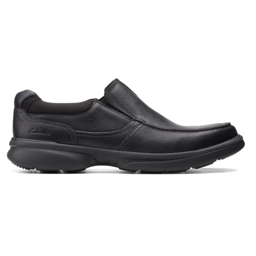 A black slip-on shoe with a sturdy rubber sole and leather upper, featuring subtle stitching and a minimalist design.