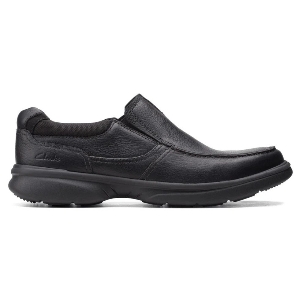 A black slip-on shoe with a sturdy rubber sole and leather upper, featuring subtle stitching and a minimalist design.