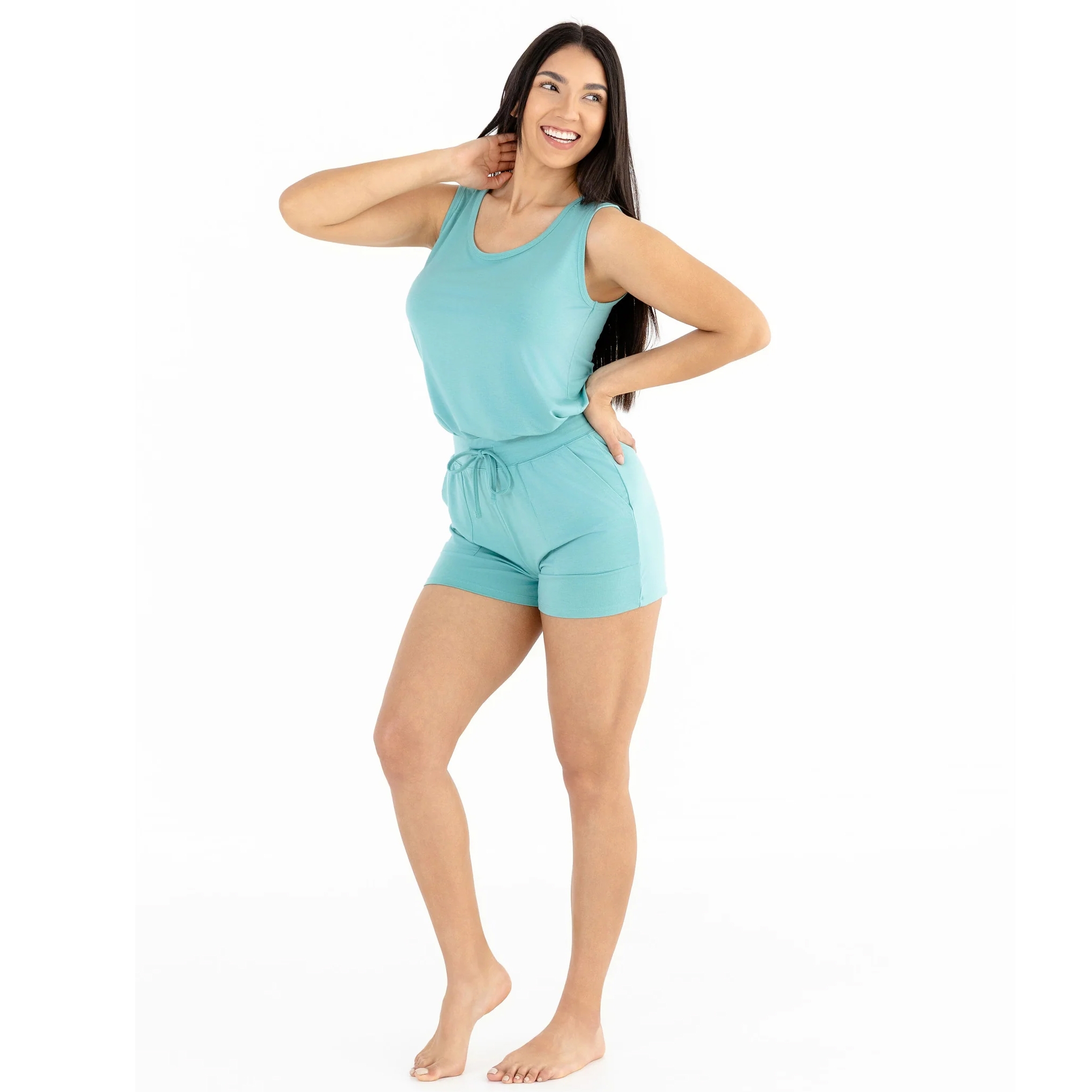 A woman is wearing a light teal sleeveless romper with a drawstring waist and shorts.