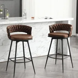 Two brown leather barstools with quilted backs and black metal legs are placed in front of a countertop with a white marble finish.