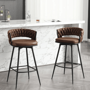 Two brown leather barstools with quilted backs and black metal legs are placed in front of a countertop with a white marble finish.