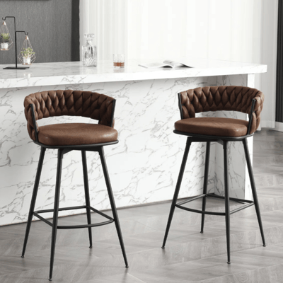 Two brown leather barstools with quilted backs and black metal legs are placed in front of a countertop with a white marble finish.