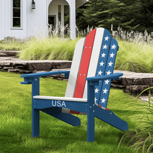 Adirondack chair with a patriotic USA design sits on a lawn in front of a white house surrounded by greenery.