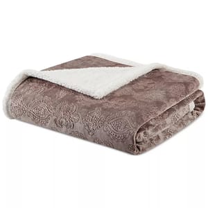 A folded, embossed plush throw blanket with a brown floral pattern and a white sherpa lining is displayed.