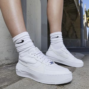 A pair of white high-top sneakers with matching white crew socks.