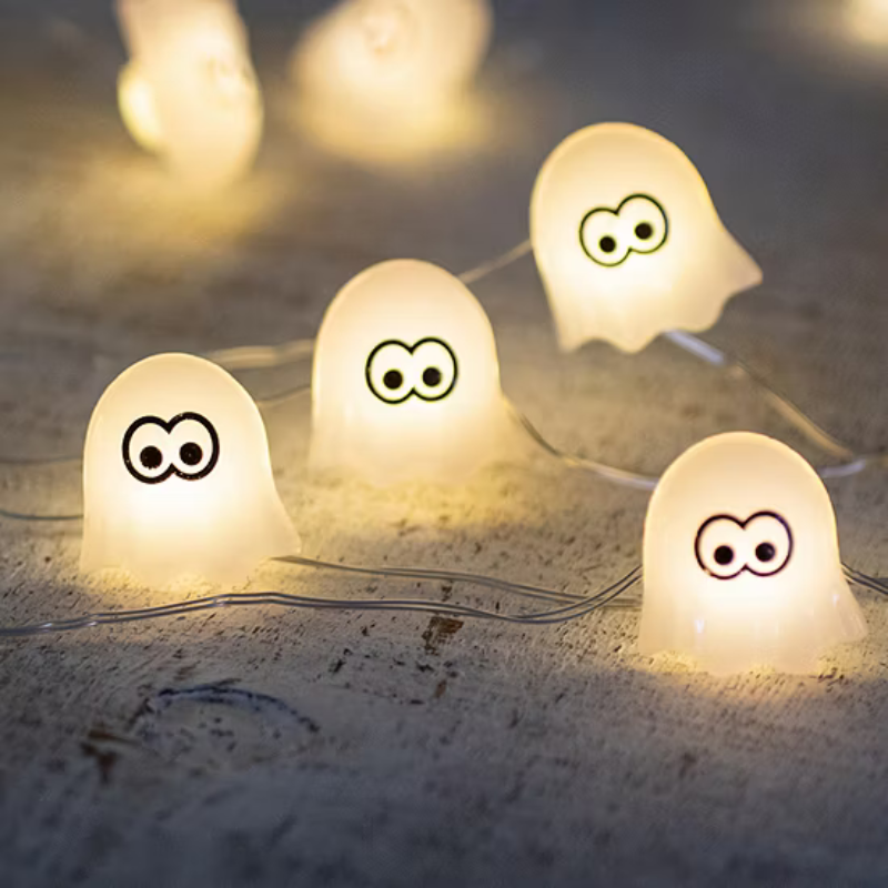 String lights featuring small, ghost-shaped covers with cartoon eyes, emitting a warm glow, suitable for festive or playful decorations.