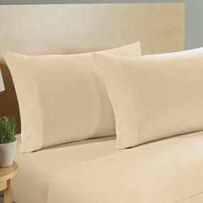A 1000-thread count, 100% cotton queen sheet set in a cream color, featuring two pillowcases and a fitted sheet, displayed on a bed.