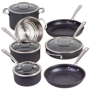 A set of black non-stick cookware with stainless steel handles, including various pots, pans, and a steamer insert, all with glass lids.