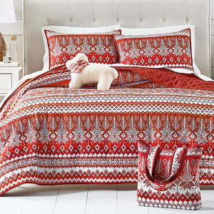 A red and white patterned bedding set with matching pillows and a tote bag, accompanied by a small white plush dog.