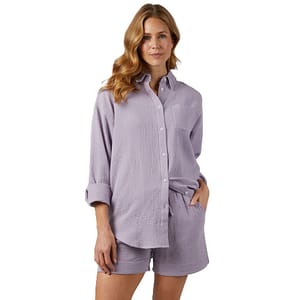 A woman is wearing a matching set consisting of a light purple, textured, long-sleeve button-up shirt and shorts.